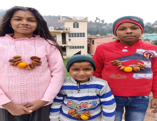 Childrens wearing garlands of sweetmeats called ghughuti mala in Uttarakhand during Ghughutiya festival